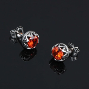 Boucles d'oreilles en acier titane avec serti couronne et cristal orange sur fond noir