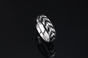 Close-up of titanium steel tire tread ring with black chevron pattern on black background