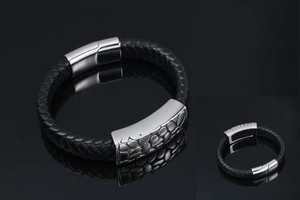 Detail view of woven black leather bracelet with textured silver magnetic metal clasp