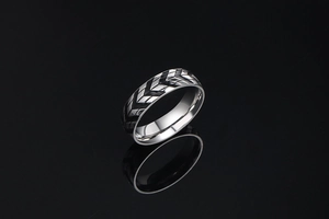 Macro detail of men's stainless steel tire tread band ring with black chevron patterns