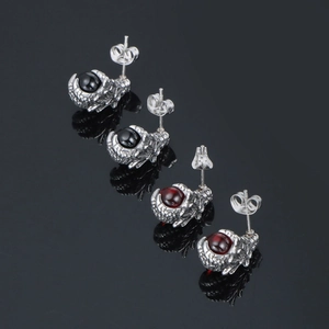 3D punk dragon claw earrings with red and black stones on a black reflective surface