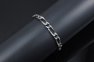 Gros plan du bracelet gourmette Figaro en argent poli sur support cylindrique