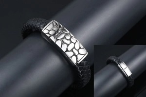 Detail of black braided leather bracelet with textured silver plate and magnetic buckle