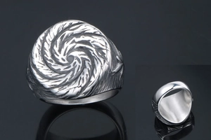 Macro shot of silver punk ring with spiral vortex texture and polished wide inner band