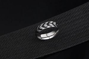 Macro shot of titanium steel men's ring with tire tread texture on black woven strap