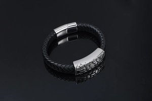 Macro view of braided black leather bracelet with textured silver metallic clasp