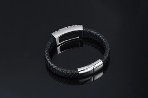 Macro shot of black braided leather texture and silver magnetic clasp with embossed plate