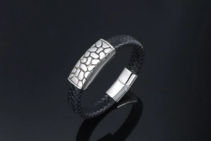 Detail of black braided leather bracelet with textured silver stainless steel plate