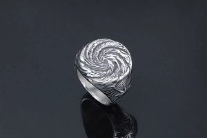 Macro shot of silver titanium ring with spiral vortex pattern and star relief