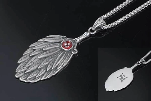 Macro detail of retro feather pendant featuring red gemstone and star engraving back