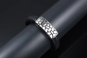 Detail of woven black leather bracelet with textured silver stainless steel buckle