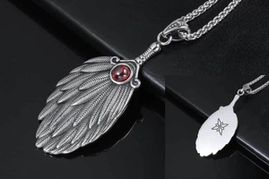 Detail of vintage feather pendant with red ruby inlay and woven chain on black base