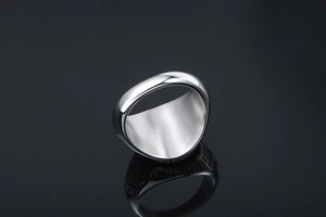 Close-up of a thick silver titanium steel ring with a brushed texture inner surface