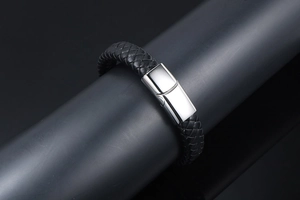 Detail of black woven leather strap with polished silver magnetic clasp on a black display stand