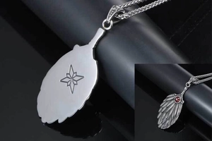 Macro detail of silver feather pendant with red gemstone and star engraving pattern