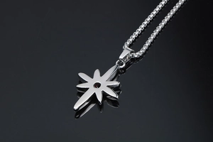 Close-up of starburst pendant with red gemstone on a silver-toned box chain necklace