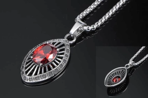 Detail view of pear-shaped red zircon pendant with intricate mesh engraving and silver chain