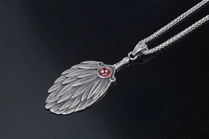 Detailed macro view of feather fan pendant with a red gemstone on a silver chain