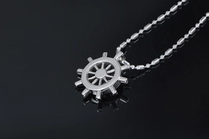 Detailed view of silver helm pendant with bead chain on reflective black background