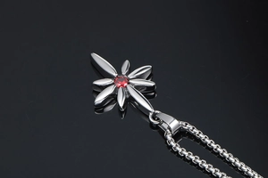Macro view of silver star pendant with a faceted red ruby stone on black mirror background