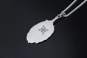 Macro view of silver leaf pendant back with engraved compass star and wheat chain