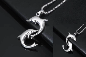 Close-up of a silver dolphin pendant necklace on a black leather background