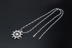 Macro detail of silver nautical rudder pendant with diamond inlay and ball chain