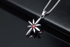 Close-up of punk style cross star pendant with red gemstone and silver box chain