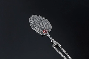 Macro detail of antique fan pendant with red ruby stone and distressed metal texture