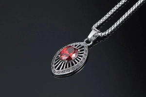 Close-up of red oval zircon pendant with unique radial grid pattern on silver box chain