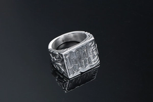 Macro shot of silver titanium steel square signet ring with star and textured carvings