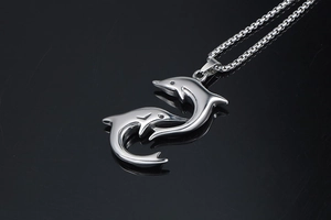 Macro shot of silver dolphin pendant with polished metallic finish on reflective surface