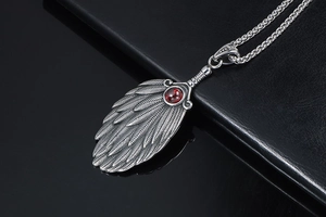 Macro shot of vintage feather pendant with red ruby inlay and detailed metal texture