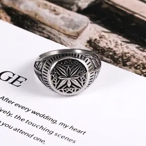 Vintage stainless steel signet ring with engraved cross pattern on dark stone background