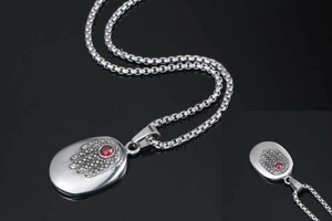 Macro shot of silver Hamsa pendant with red gemstone inlay on a box chain necklace