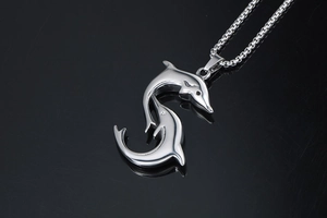 Detailed macro view of silver twin dolphin pendant on a stainless steel chain