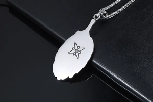 Close-up of silver feather pendant with engraved star and wheat chain on leather