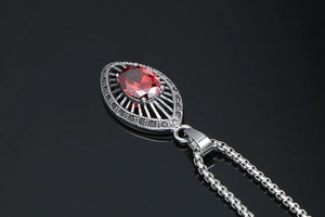 Macro detail of red oval gemstone pendant with vintage hollow metalwork and box chain