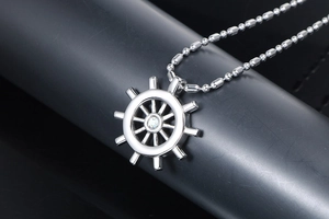 Macro detail of silver ship wheel pendant with sparkling central stone on bead chain