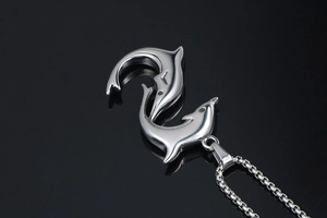 Detail shot of two dolphins forming an S-shape on a polished silver box chain necklace