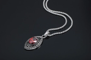 Macro view of teardrop red gemstone pendant with radial cutout design on black background