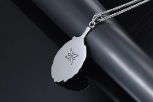 Macro detail of silver feather pendant necklace featuring engraved star on the back