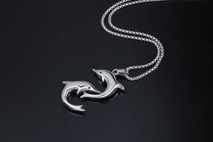 Macro view of polished stainless steel double dolphin pendant with mirrored finish
