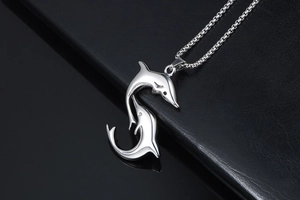 Macro shot of silver dolphin pendant on box chain over black leather background