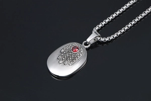 Macro view of Hamsa Hand pendant with a red gemstone and silver-toned box chain