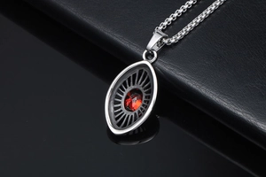 Macro detail of tear-drop eye pendant with red zircon stone and silver textured steel chain