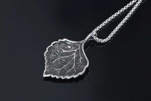Detailed macro view of vintage leaf pendant with intricate vein texture and box chain