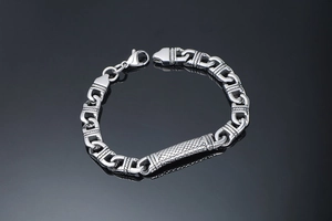 Macro shot of stainless steel curb chain bracelet with diamond pattern metal bar