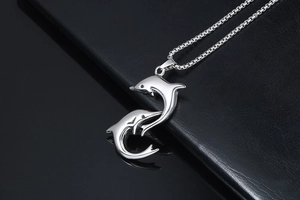 Macro shot of polished stainless steel double dolphin pendant on a fine box chain