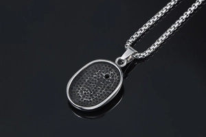 Macro detail of silver stainless steel necklace pendant with black honeycomb texture back